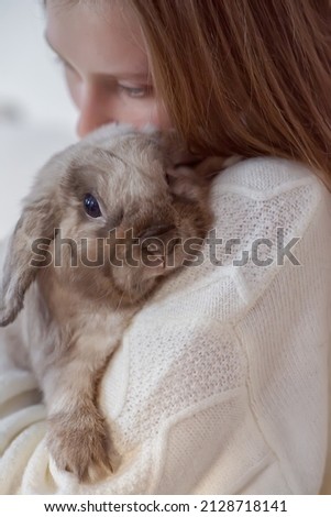 Girl hugs a cute white rabbit at home.a girl with a rabbit, bunny pet. close up