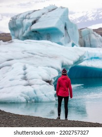 girl in icelandic knitted cap standing in front of huge, monumental icebergs in iceland, glacier lagoon - Shutterstock ID 2202757327