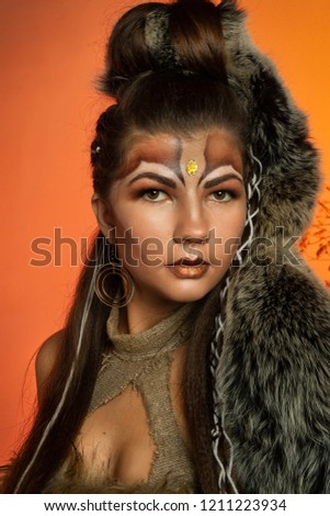 The girl in the image of the Amazon, with a fantasy make-up, posing in the studio. Closeup portrait.