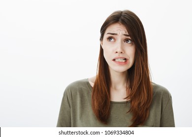 Girl imagining bad consequences of her action. Regretting worried beautiful woman in dark-green t-shirt, frowning and looking up while thinking or feeling guilty, remembering something awkward