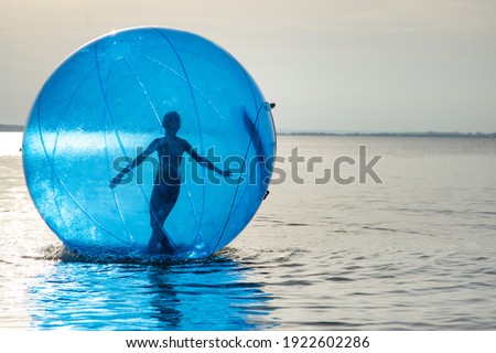 A girl in an inflatable attraction in the form of a ball on the sea