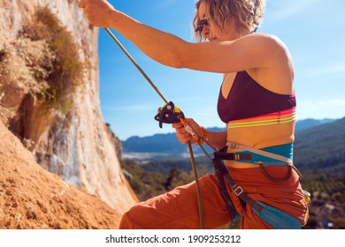 the girl insures her partner while climbing the mountains. rock climbing safety and insurance concept. healthy lifestyle and sports in nature on a sunny day.
