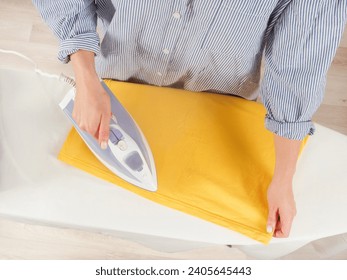 Girl ironing clothes with an iron on an ironing board selective focus close-up - Powered by Shutterstock