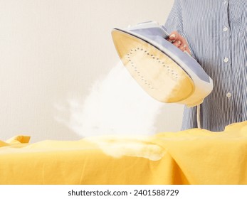 A girl irons clothes with an iron, household chores, clothing care close-up - Powered by Shutterstock