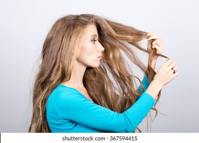 Girl irritated with her very long gorgeous hair holding scissors 