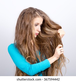 Girl irritated with her very long gorgeous hair holding scissors 