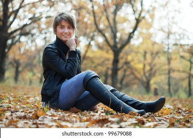 Girl in jacket and black knee-high boots at autumn park