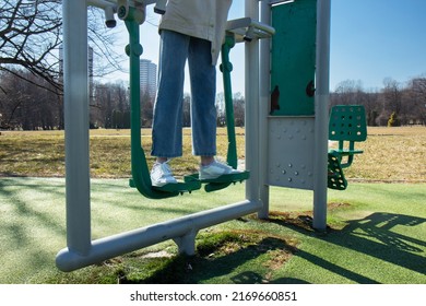 Girl in jeans walks on playground. Active pastime on the simulator in the fresh air