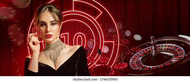 Girl in jewelry and black dress. Showing two red chips, posing on colorful background with neon lights, roulette and chips. Poker, casino. Close-up - Powered by Shutterstock