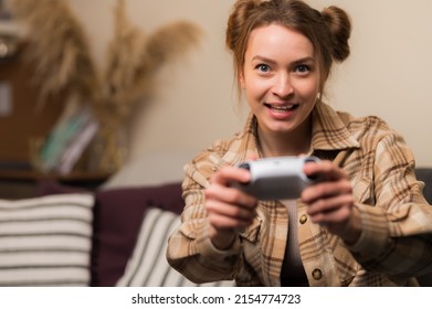 A girl with a joystick enthusiastically plays a video game. Close-up. Fun pastime, online video games with friends, communication, youth culture, adventure games, virtual reality.