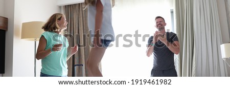 Girl jump on bed. Dad look at his daughter and claps his hands. Mom look at her husband and smile.