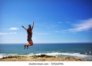 Girl Jumping By Pacific Ocean Beach with Waves Landscape from California Highway 1 - Powered by Shutterstock