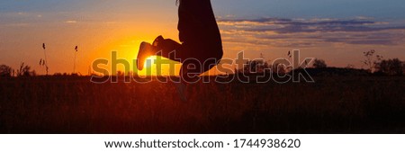 girl jumping in field at sunset