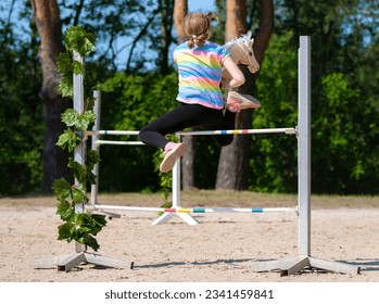 Girl jumping on hobby horse. Champion. Horse sport. Summer light. Green outdoor trees background. The Cavaletti route. Child sport. Banner - Shutterstock ID 2341459841