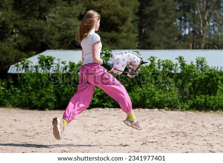 Girl jumping on hobby horse. Champion. Horse sport. Summer light. Green outdoor trees background. The Cavaletti route. Child sport. Banner