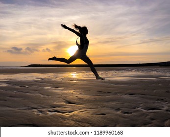 Girl jumping at sunset over the ocean.