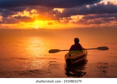 Girl Kayaking On An Inflatable Kayak In Howe Sound. Dramatic Sunset Sky Art Render. Taken In West Vancouver, BC, Canada. Concept: Adventure, Sport, Fun