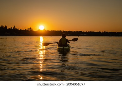 Girl kayaking and taking pause calm sea at midnight in Northern Sweden during light Summer nights. All day around Sun in polar regions. - Shutterstock ID 2004061097