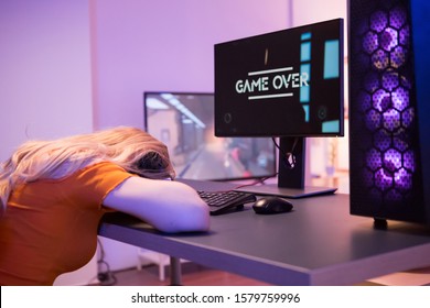 Girl Keeping His Head On Desk Office After She Lost On Computer Game. Game Over. Girl Sitting On Gaming Chair.