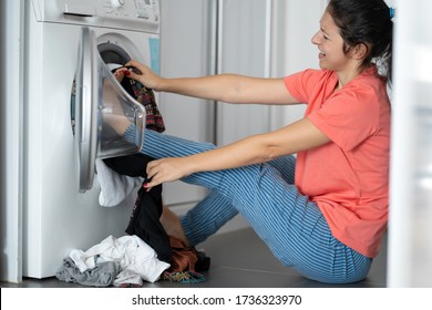 Girl Kicks Dirty Laundry In The Washing Machine. A Lot Of Dirty Clothes That Do Not Fit In A Washing Machine. Laundry Day, Housework.