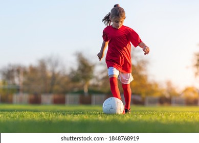 Girl kicks a soccer ball on a soccer field