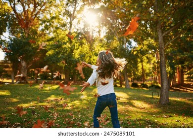 Girl, kid and playing in park with leaves for adventure, fun activity or spinning with enjoyment in autumn. Child, back and outdoor with freedom, holiday and wellness on grass in nature with sunlight - Powered by Shutterstock