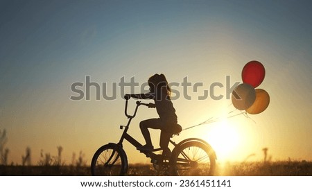 girl kid silhouette bike riding on a park. kid girl rides a bike in nature in park on the road. happy family kid dream concept. daughter plays a bike lifestyle rides on a sandy road