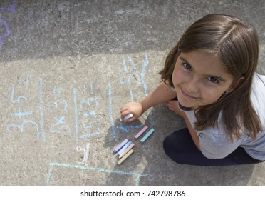 Girl kid thinking  writing   counting mathematical equations and colored chalks pavement  School   vacation concept  Education concept  School   fun time 