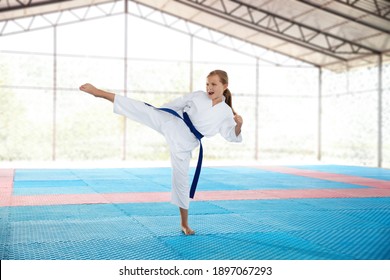 Girl in kimono practicing karate on tatami outdoors