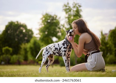 girl kissing dalmatian dog in the park, love for dog and animals - Powered by Shutterstock