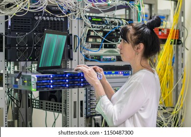 A Girl With A Laptop Works In The Server Room. The Woman Downloads The Software On A Powerful Networked Internet Equipment. The System Administrator Is In The Datacenter