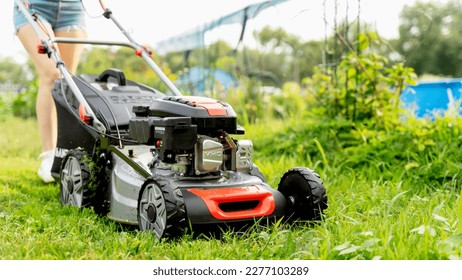 a girl with a lawn mower mows a green lawn. High quality photo