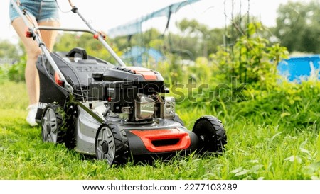 a girl with a lawn mower mows a green lawn. High quality photo Stockfoto © 