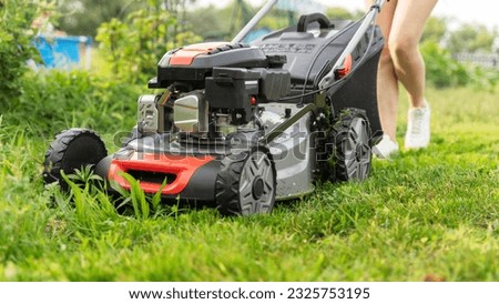 a girl with a lawn mower mows the lawn. High quality photo