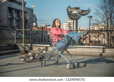 Girl laying in the Shopping Trolley and pigeons around her