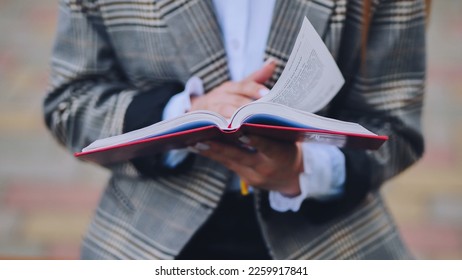 A girl is leafing through a book in the park.