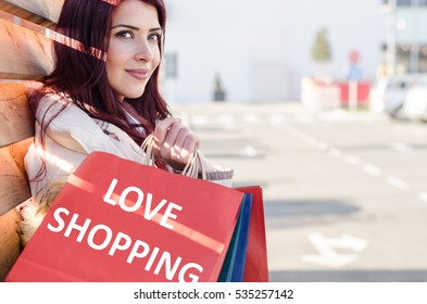 Girl Leaning On Wooden Wall Holding Shopping Bags In Hand. Shopping Maniac On The Street