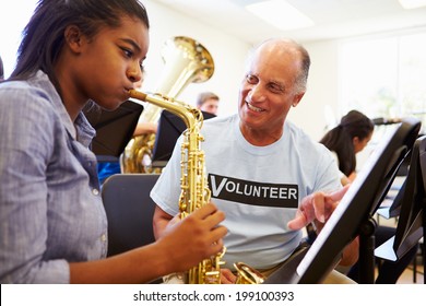 Girl Learning To Play Saxophone In High School Orchestra