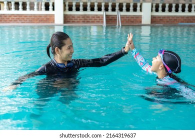 Girl Learning To Swim With Coach And Hands Tag Team At The Swimming Pool 