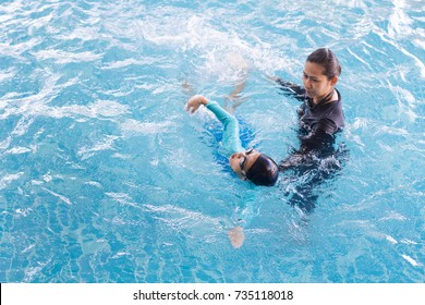 Girl Learning To Swim With Coach At The Leisure Center