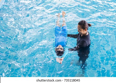 Girl Learning To Swim With Coach At The Leisure Center