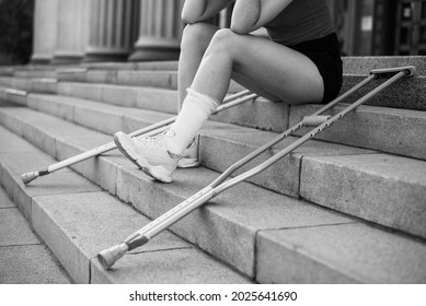 Girl With Leg Injury Sits On The Stairs With Crutches.