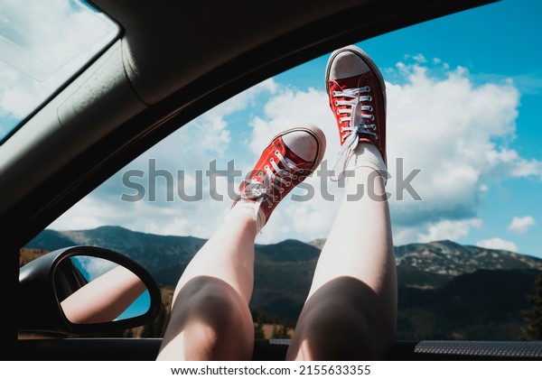 Girl\
legs in bright sneakers sticking out of the\
car\
