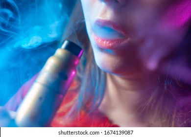 The girl lets off steam from the VAPE. Smoking an electronic cigarette. The concept of vaping. E-cigarette and female lips. Fashion for vaping. Accessories for Smoking electronic cigarettes.