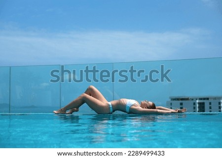 girl lies beautifully on the edge of the infinity pool against the background of the sea, the concept of relaxation, summer, vacation, spa