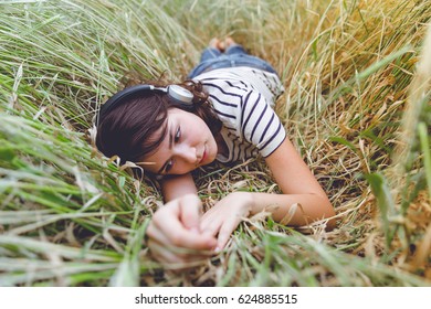 girl lies on the field with headphones on