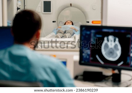 A girl lies on an MRI machine before examining her body and the radiologist gives command to her to prepare for a diagnosis