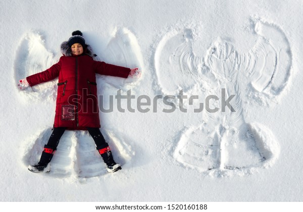 The girl\
lies in the snow and makes a snow\
angel