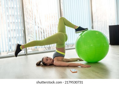 A Girl In Light Green Leggings Does Stretching In An Elite Gym In Front Of A Mirror. The Concept Of A Healthy Body In A Woman