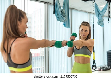 A Girl In Light Green Leggings Does Stretching In An Elite Gym In Front Of A Mirror. The Concept Of A Healthy Body In A Woman